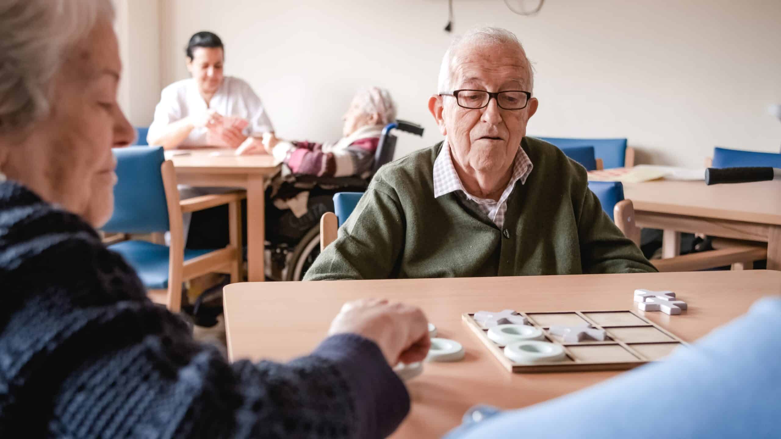 Senior man playing tic tac toe with friends in nursing home