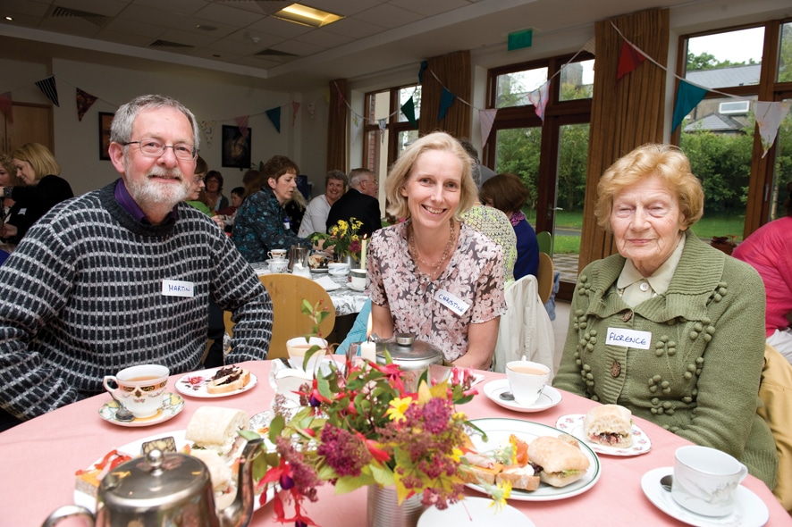 People gathered around a table, sharing food and laughter in a cozy setting.